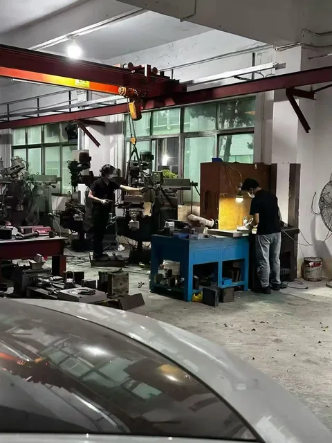 惠州工厂内两名工人在机加工与手工工作站作业