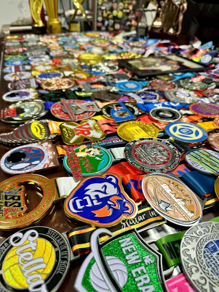 A worktable covered with custom medals in varied shapes, finishes, colors, and ribbons